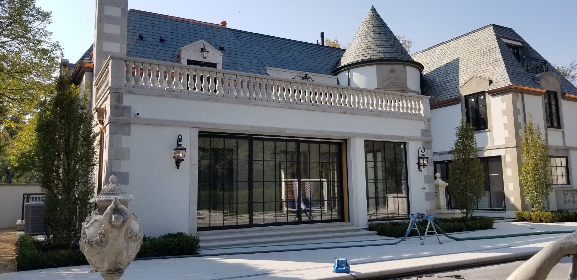 A large white house with a castle roof is sitting next to a pool.
