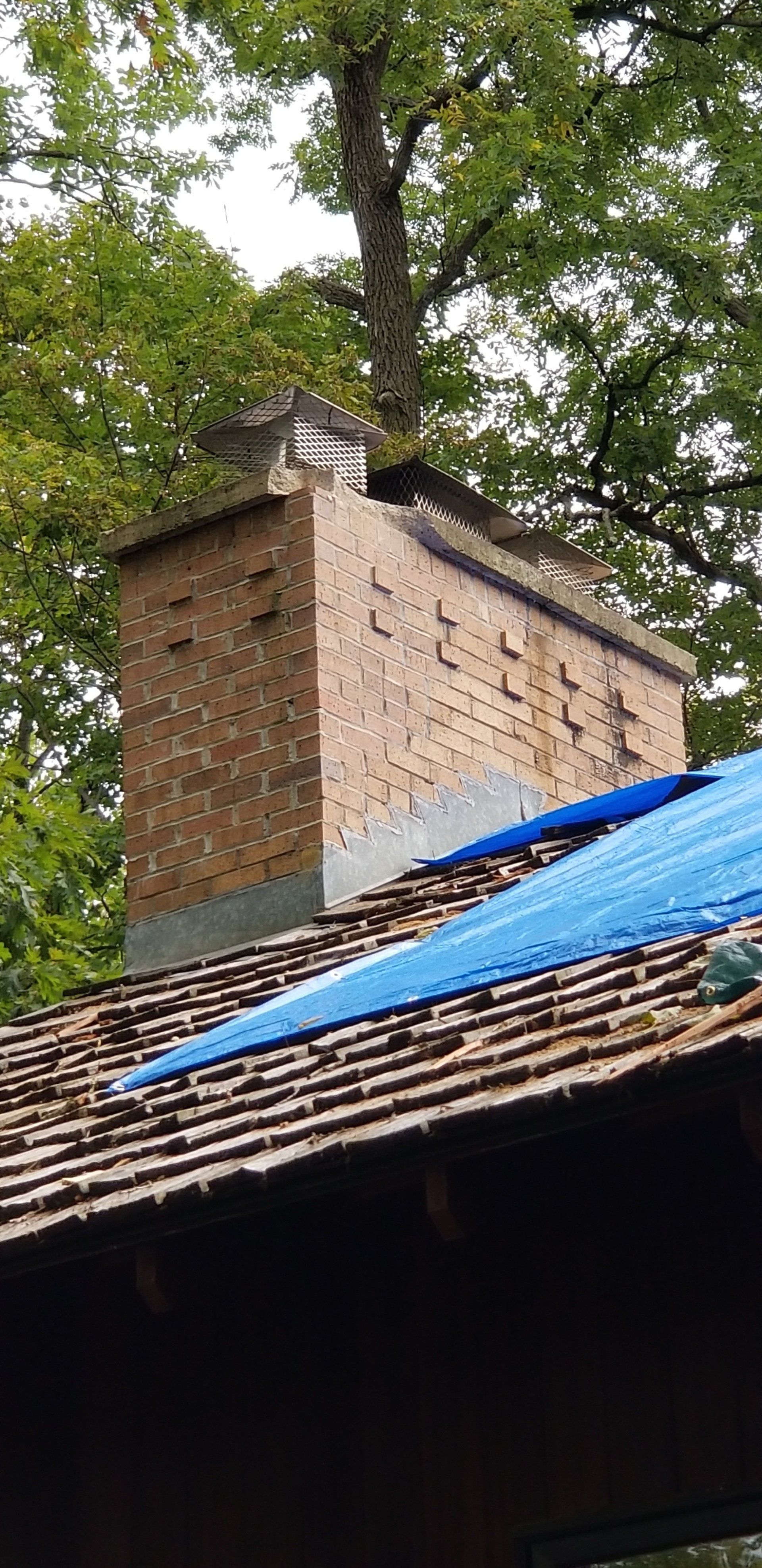 A brick chimney is sitting on top of a wooden roof.