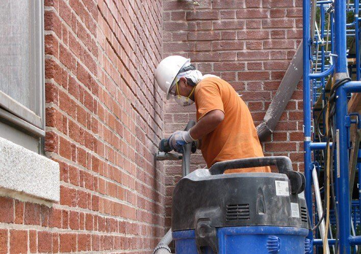 A man wearing a hard hat is working on a brick wall