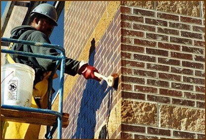 A man is painting a brick wall with a brush