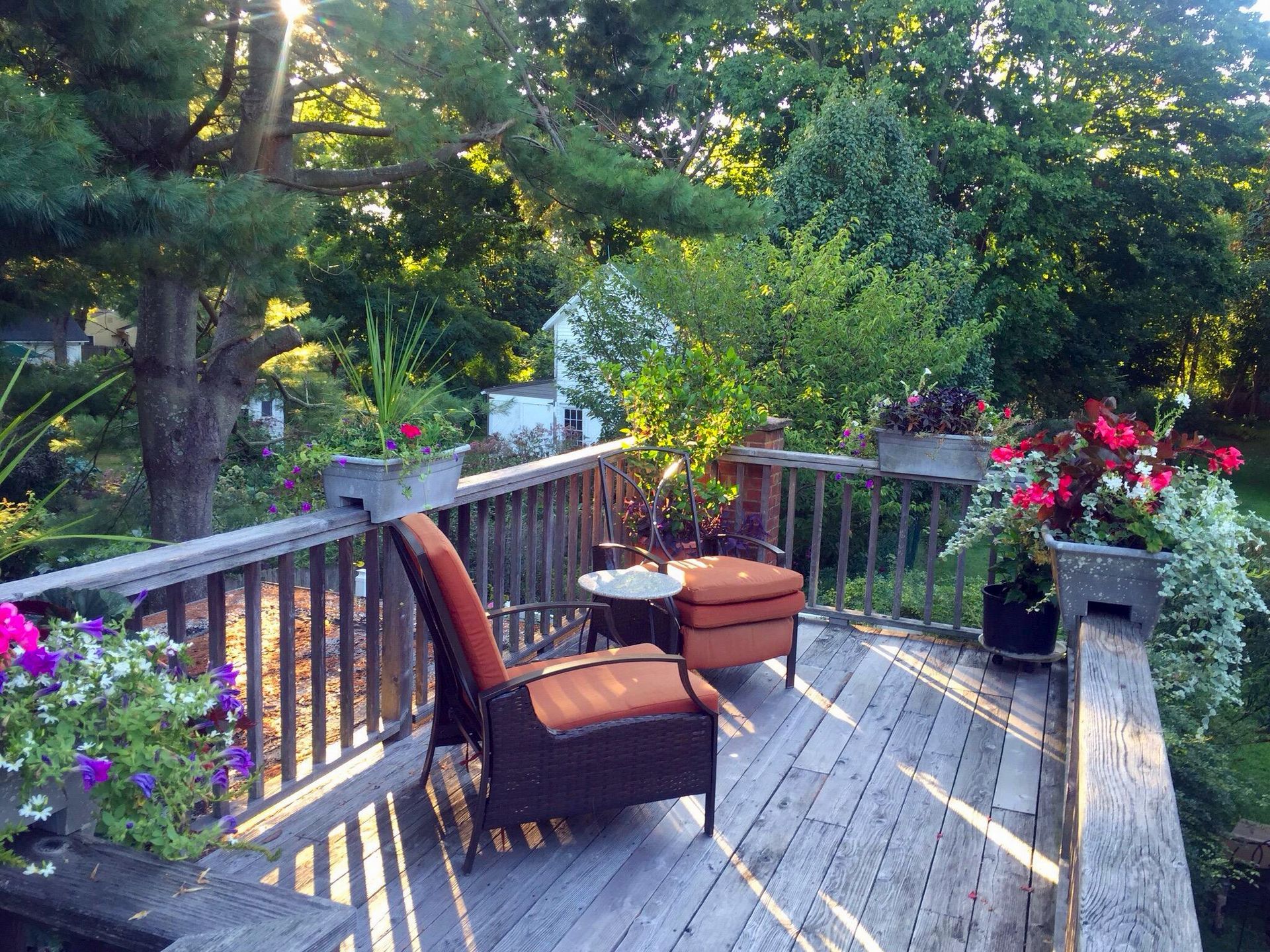 A wooden deck with chairs and flowers on it