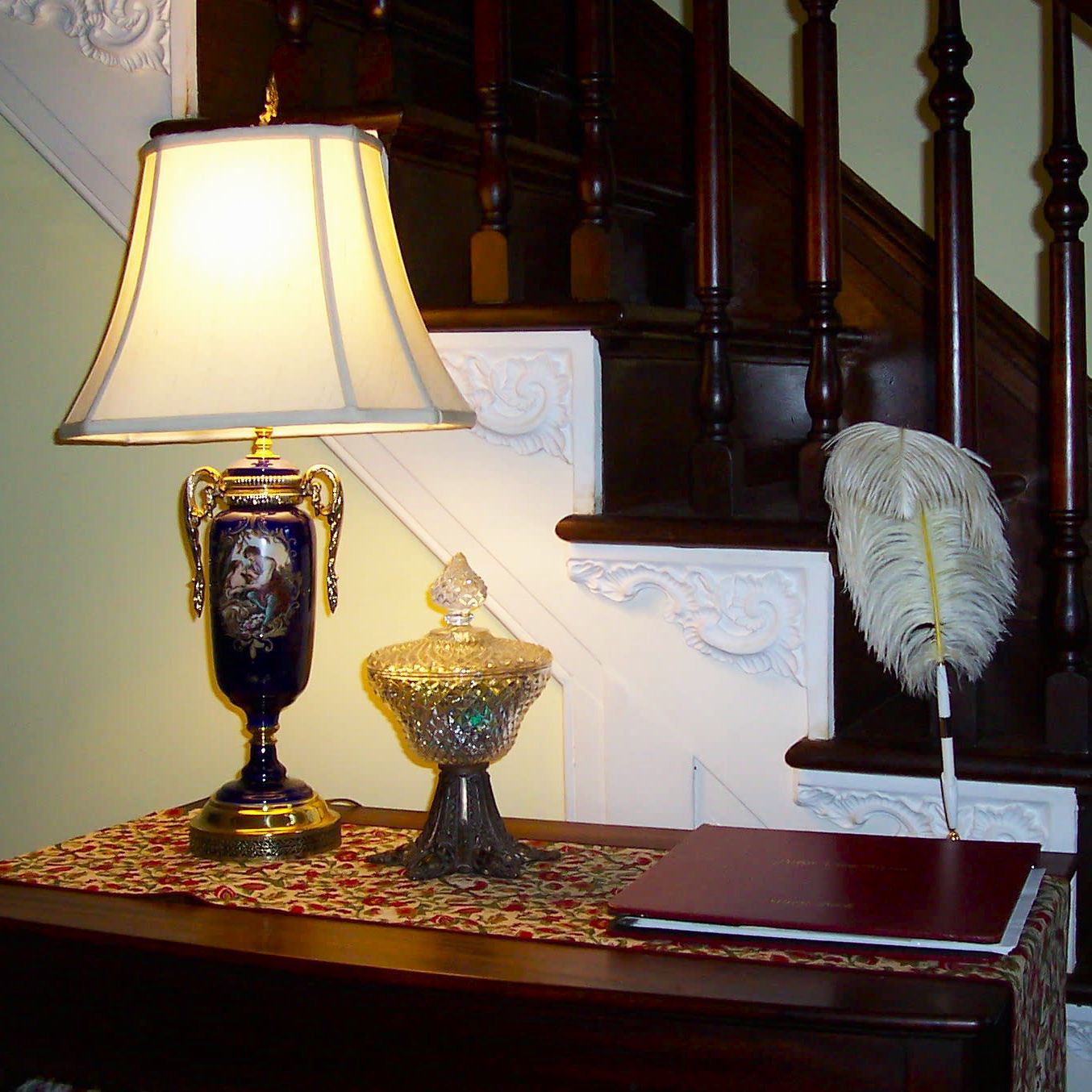 A lamp sits on a table next to a staircase