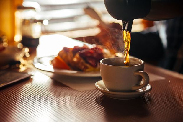 A person is pouring coffee into a cup on a table.