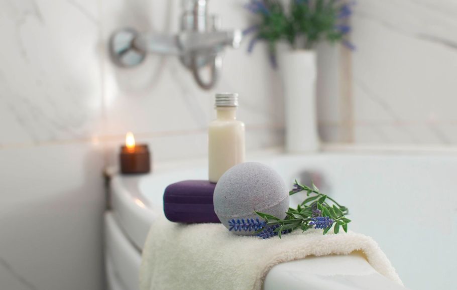 A bathtub with a towel , soap , and a candle on it.