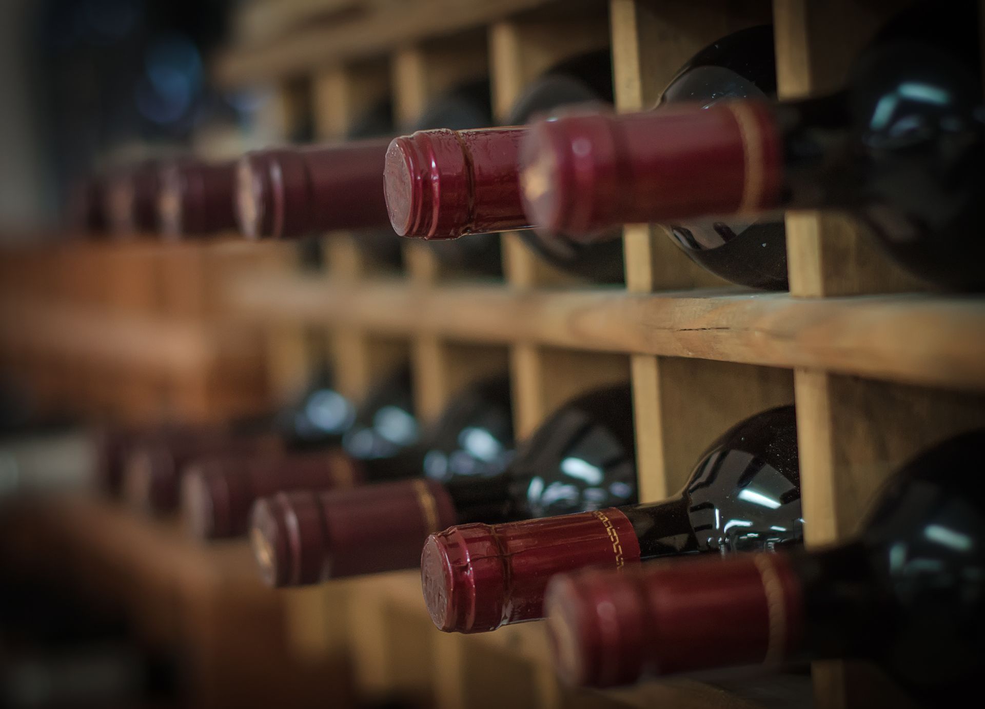 A row of wine bottles sitting on top of a wooden wine rack.