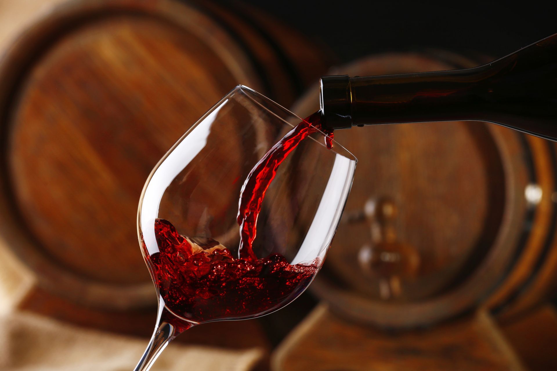 A glass of red wine is being poured from a bottle