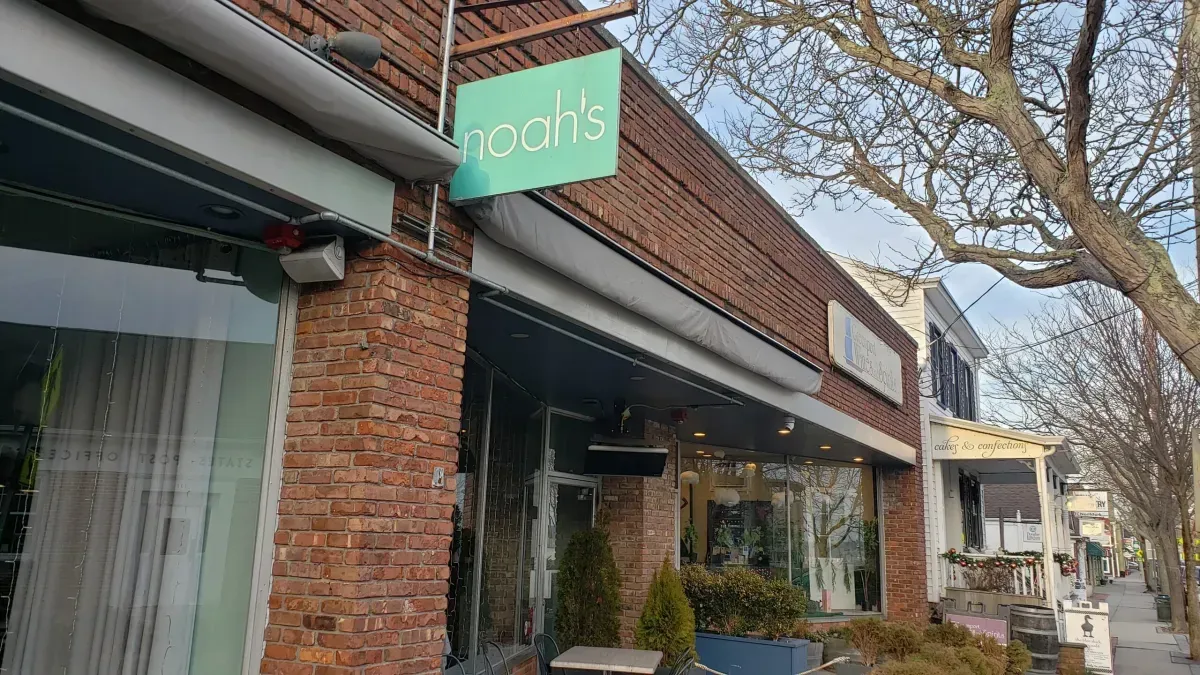 A brick building with a green sign on the side of it.