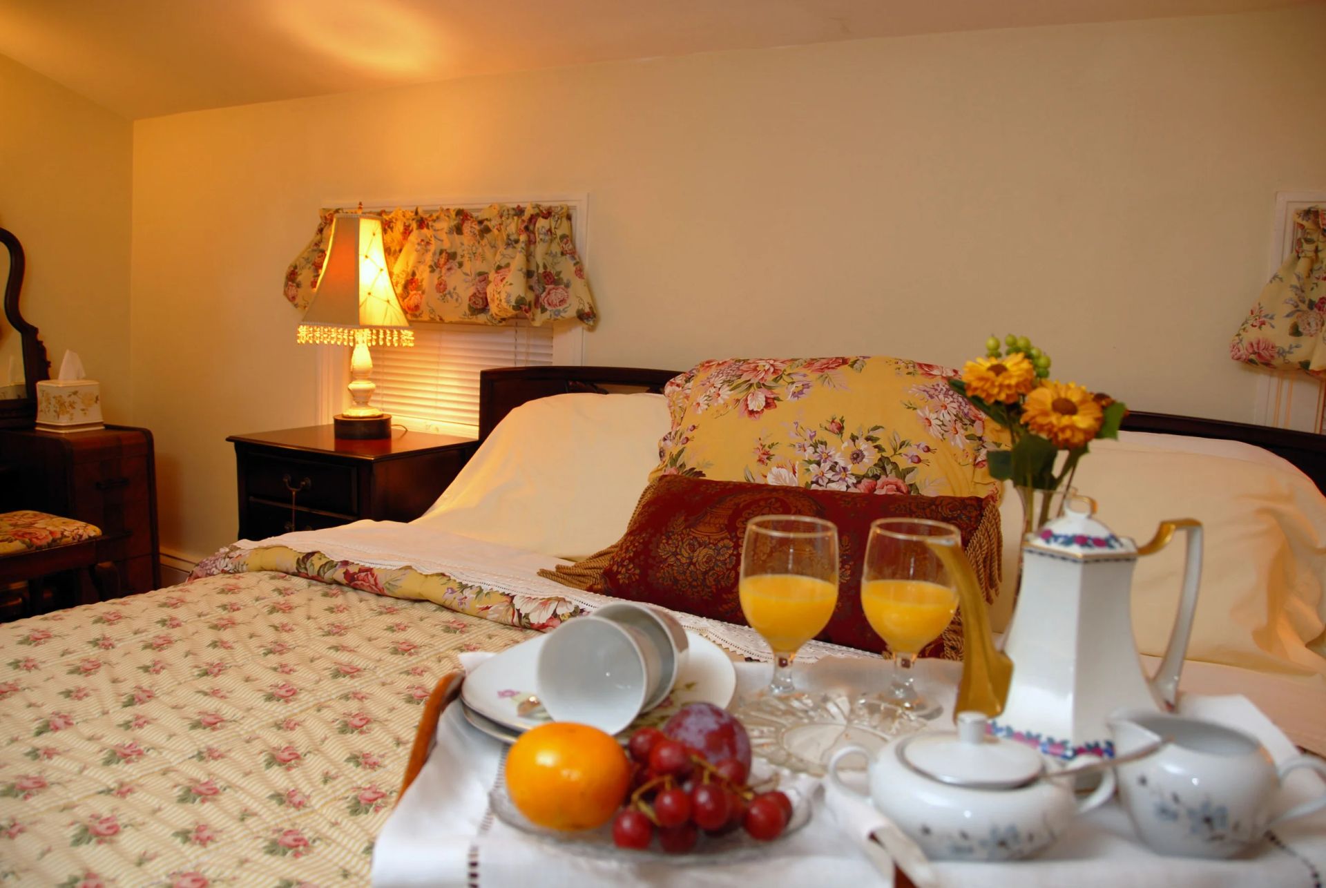 A bedroom with a large bed , chairs , lamps and a painting on the wall.