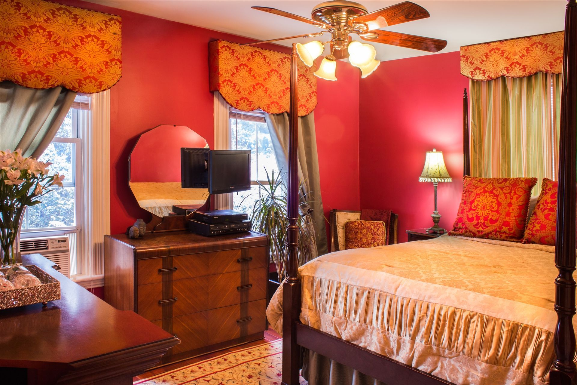 A bedroom with red walls and a four poster bed