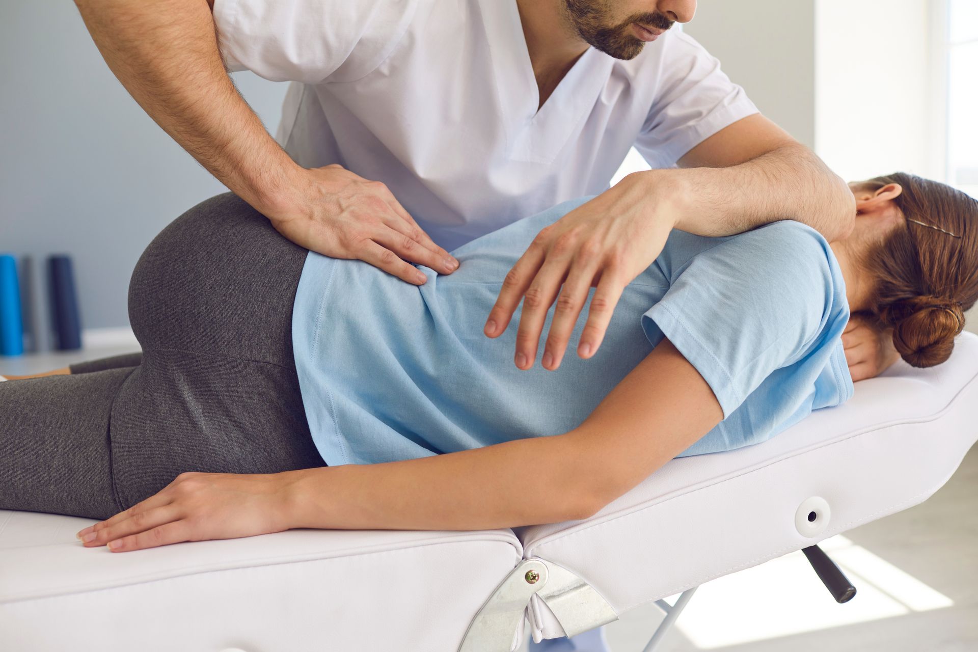 A person receiving a back examination from a doctor. White illustrated spine on the person’s back.