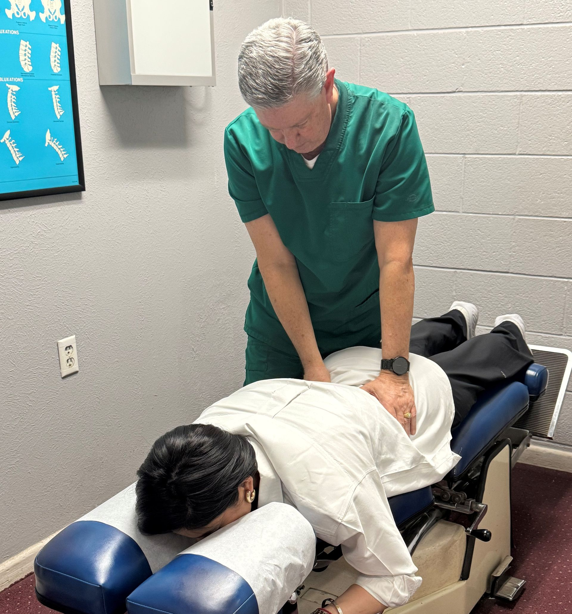 Therapist manipulating a patient's shoulder and back.