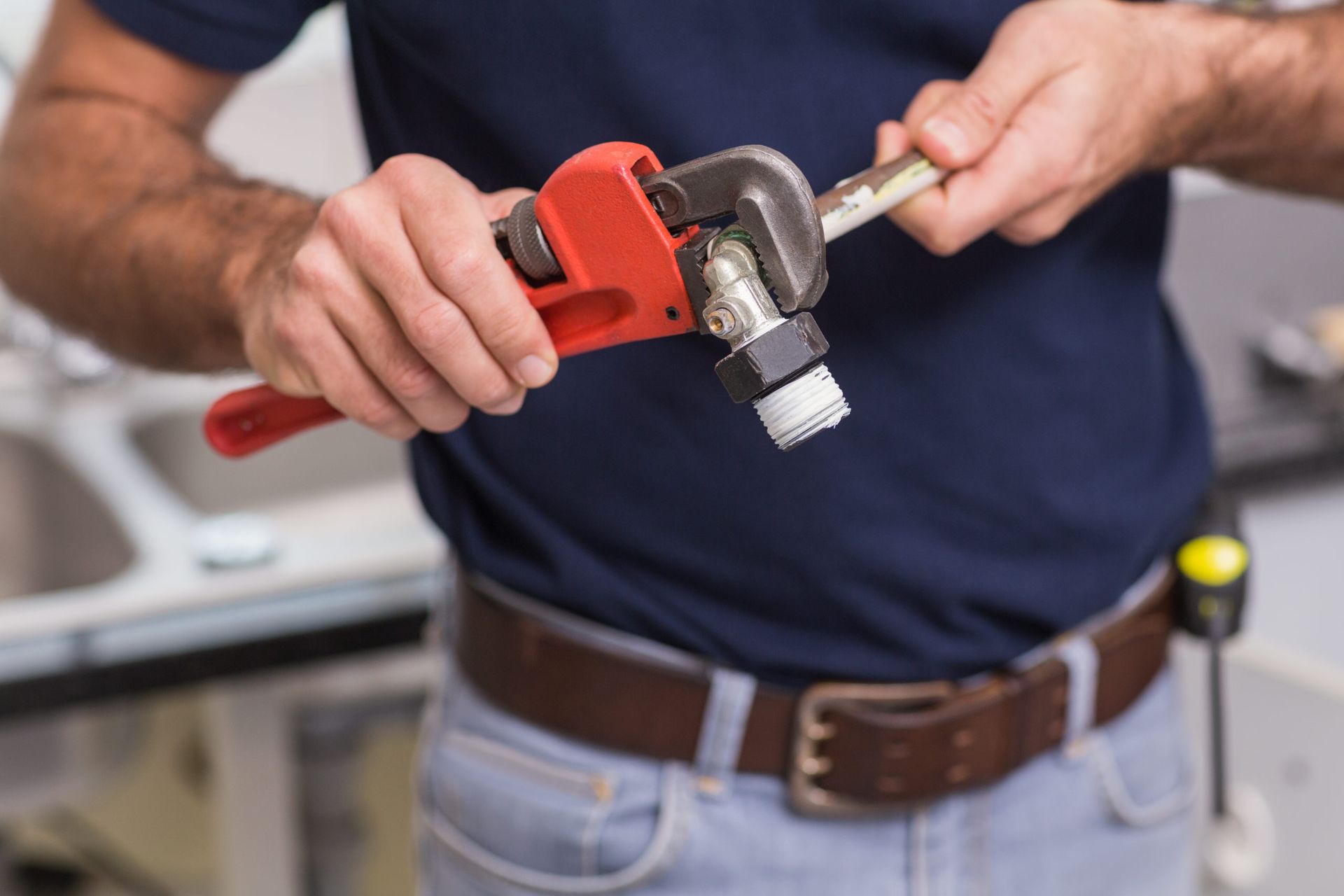 A man is fixing a pipe with a wrench.