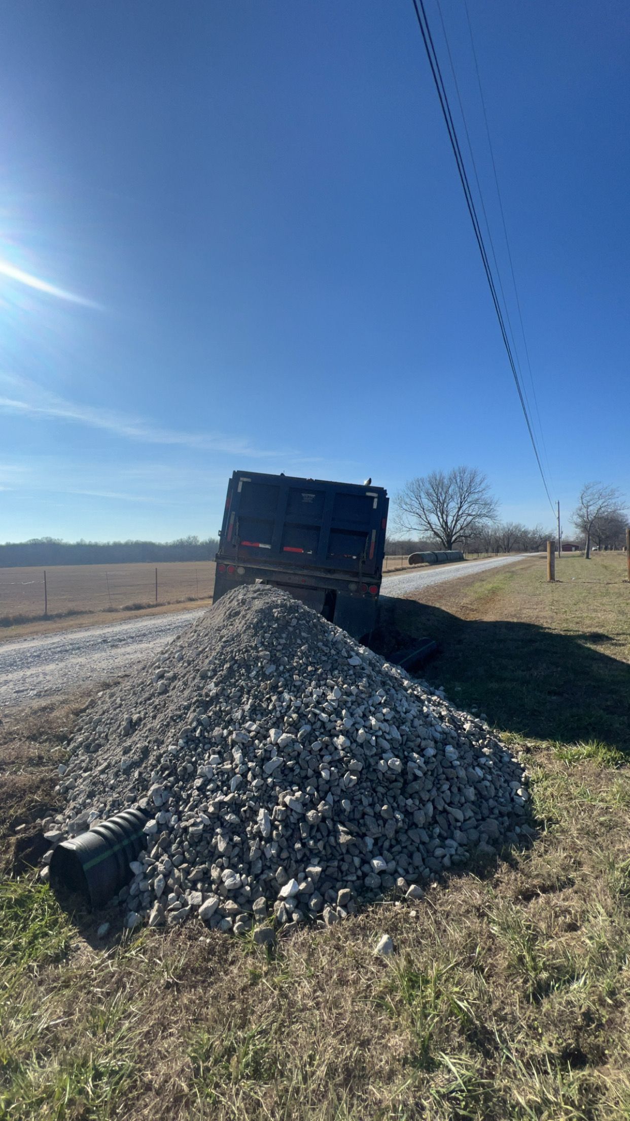 A tractor is driving down a dirt road in the woods.