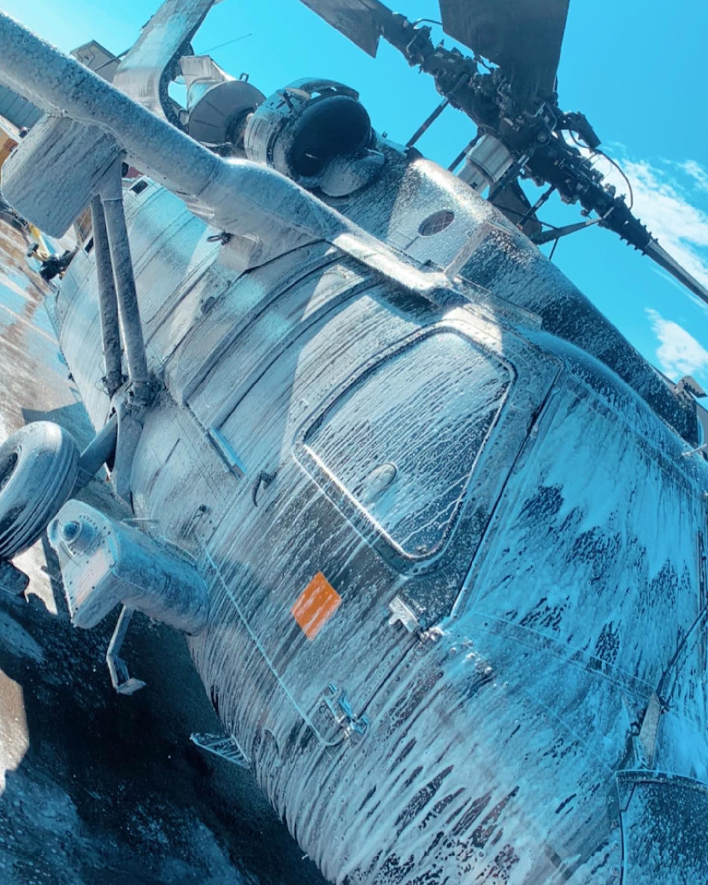 A helicopter is laying on the ground with a blue sky in the background