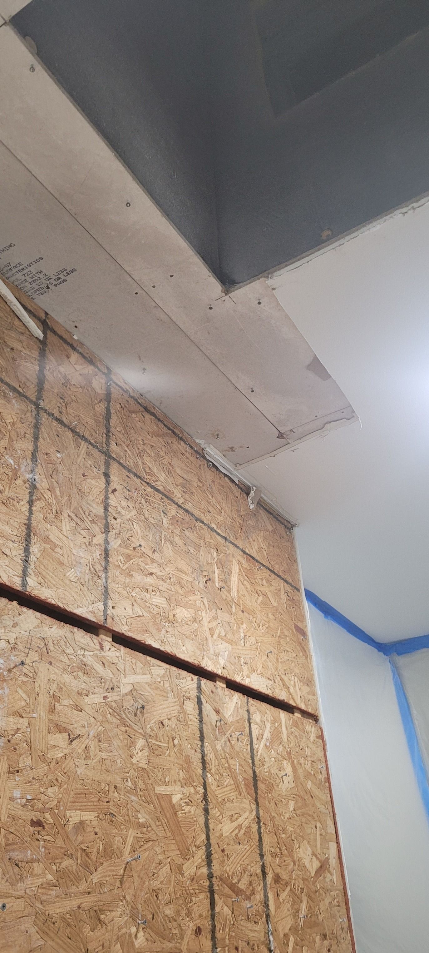 A corner of a room under construction. Wooden paneling covers the wall, and a painted ceiling is visible.