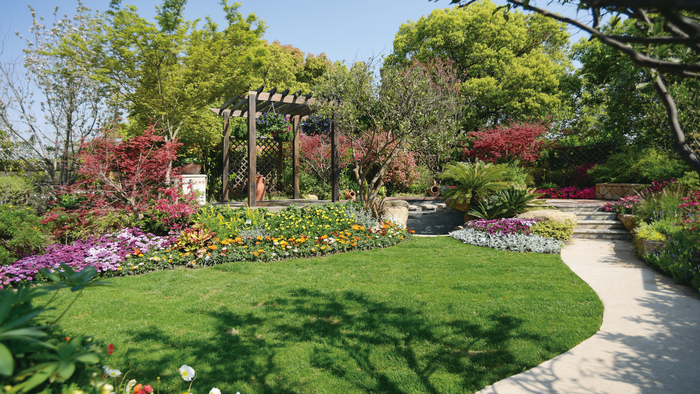 Een mooie tuin met een pad, trap en bloemenperken op een zonnige dag.