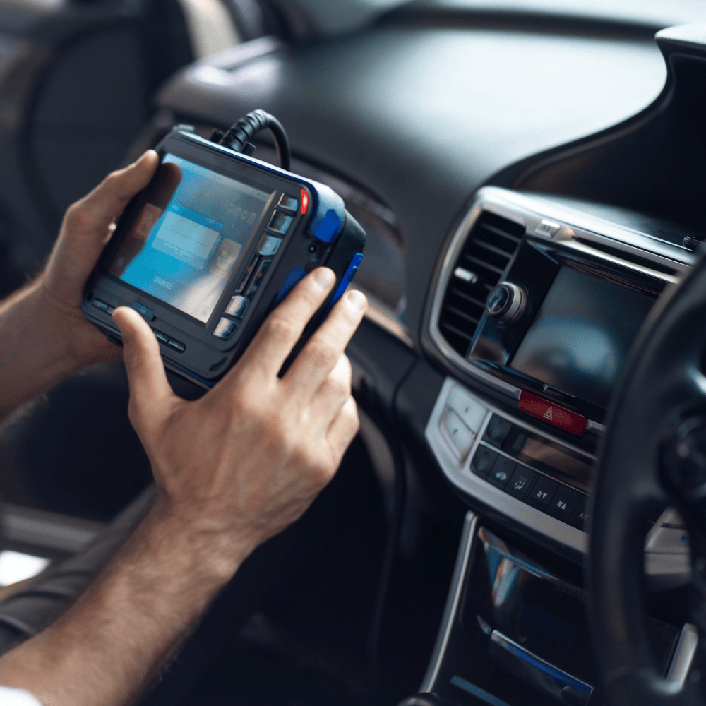 A man is holding a device in his hands in a car