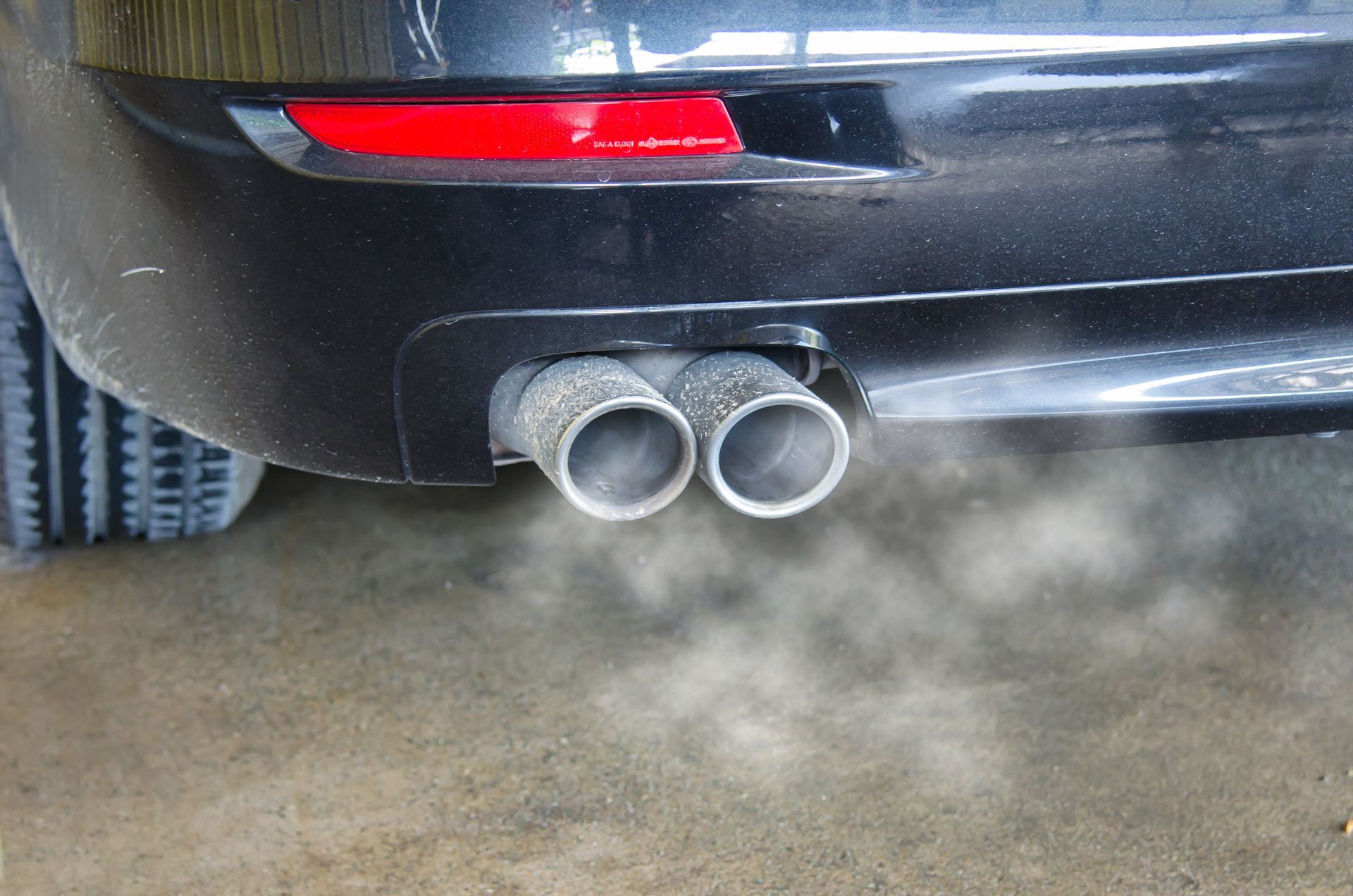 Smoke is coming out of the exhaust pipes of a car.