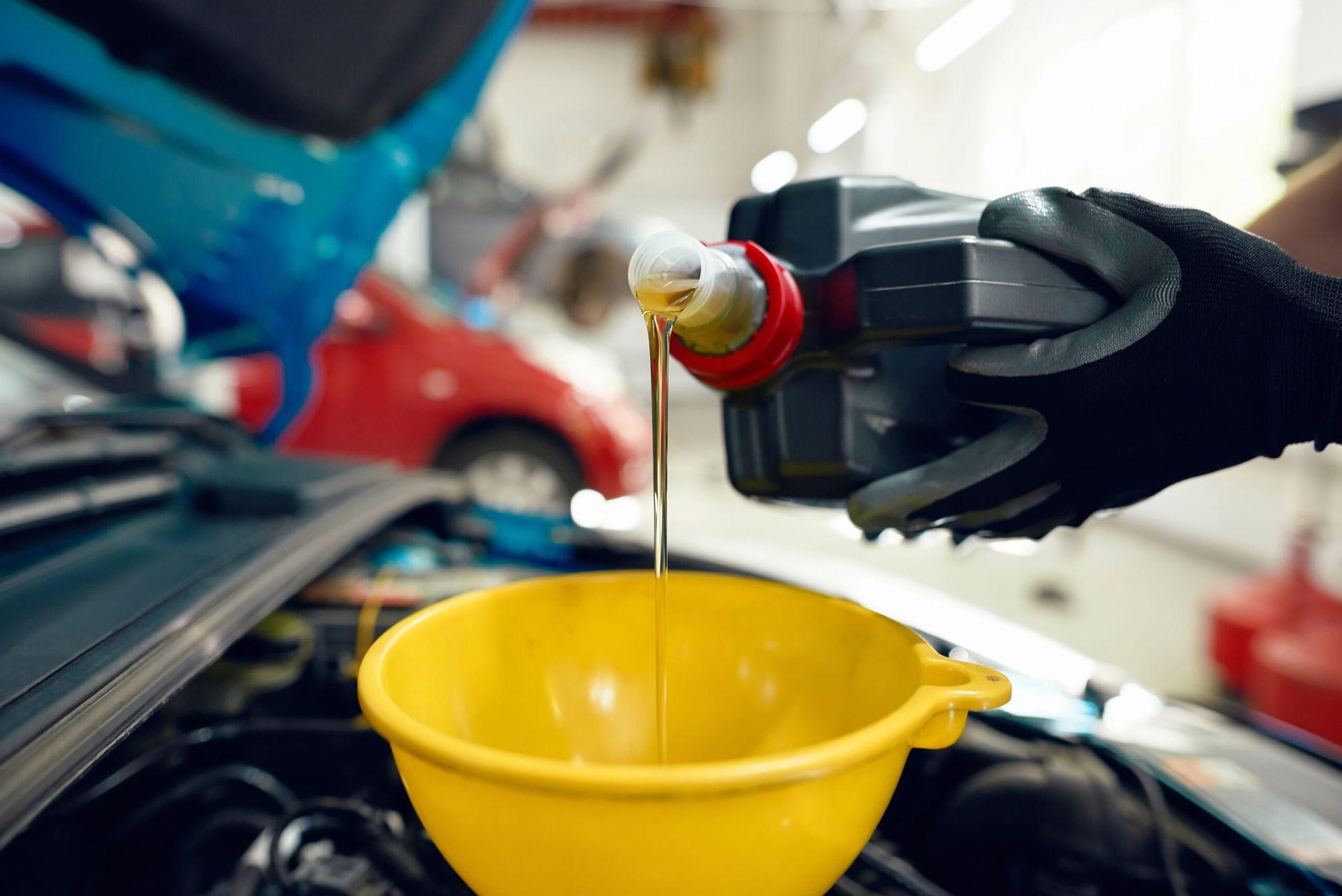 A person is pouring oil into a yellow bowl from a bottle.