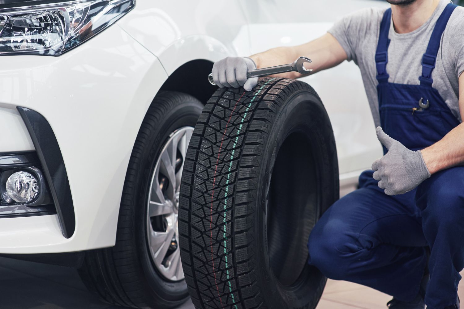A man is changing a tire on a white car.