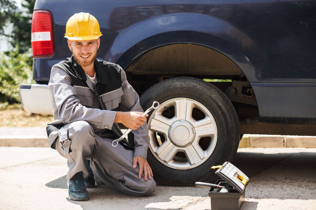 A man is changing a tire on a truck with a wrench.