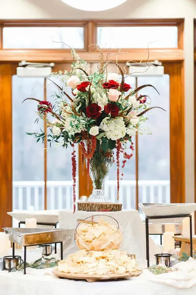 Elegant floral centerpiece with red and white flowers on a table in a bright dining room