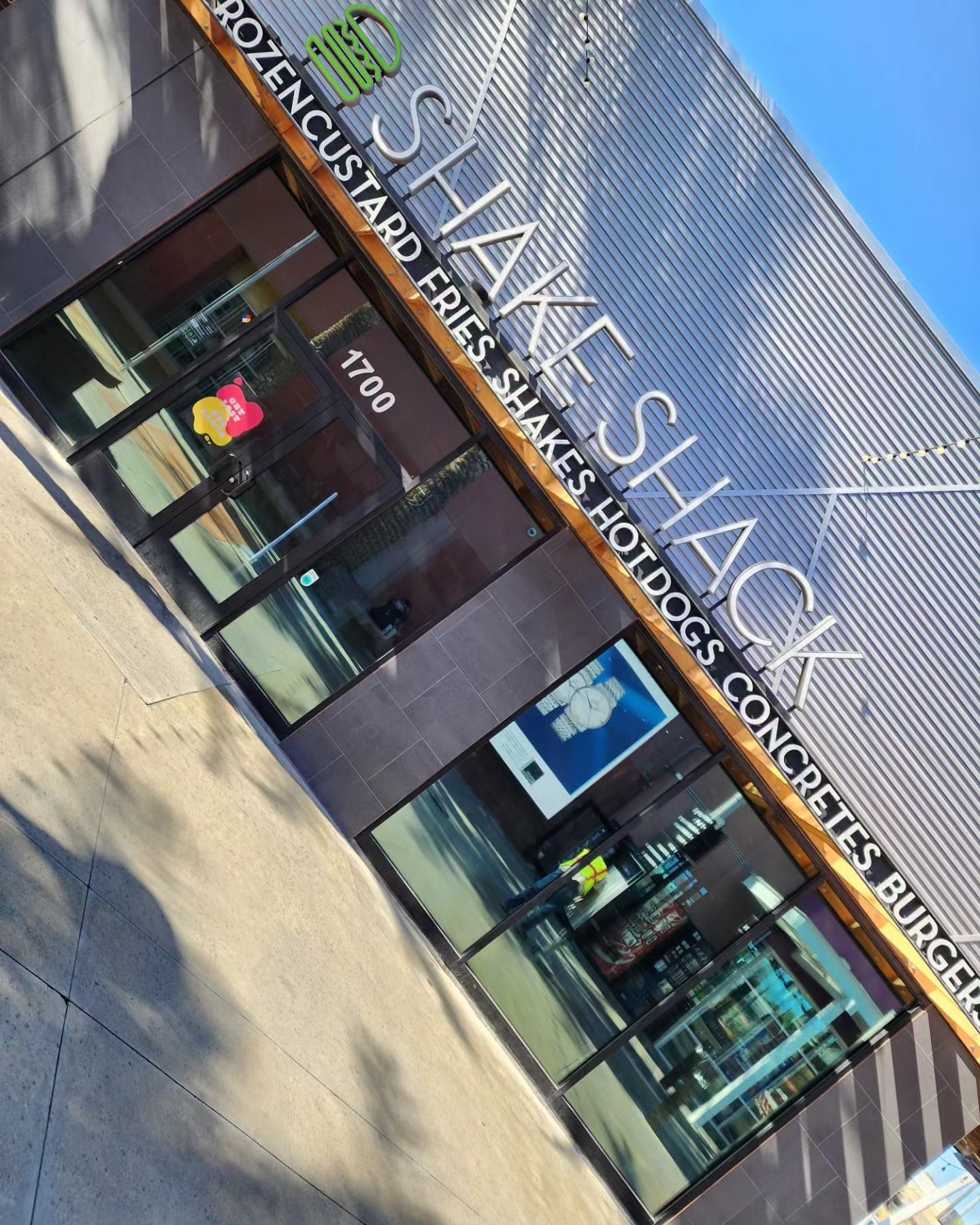The outside of a shake shack restaurant with a blue sky in the background