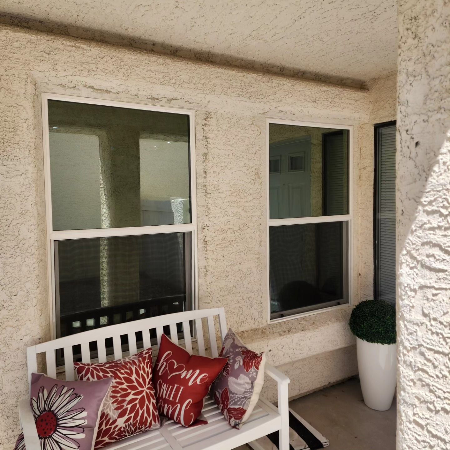 A white bench with red and white pillows on it says 