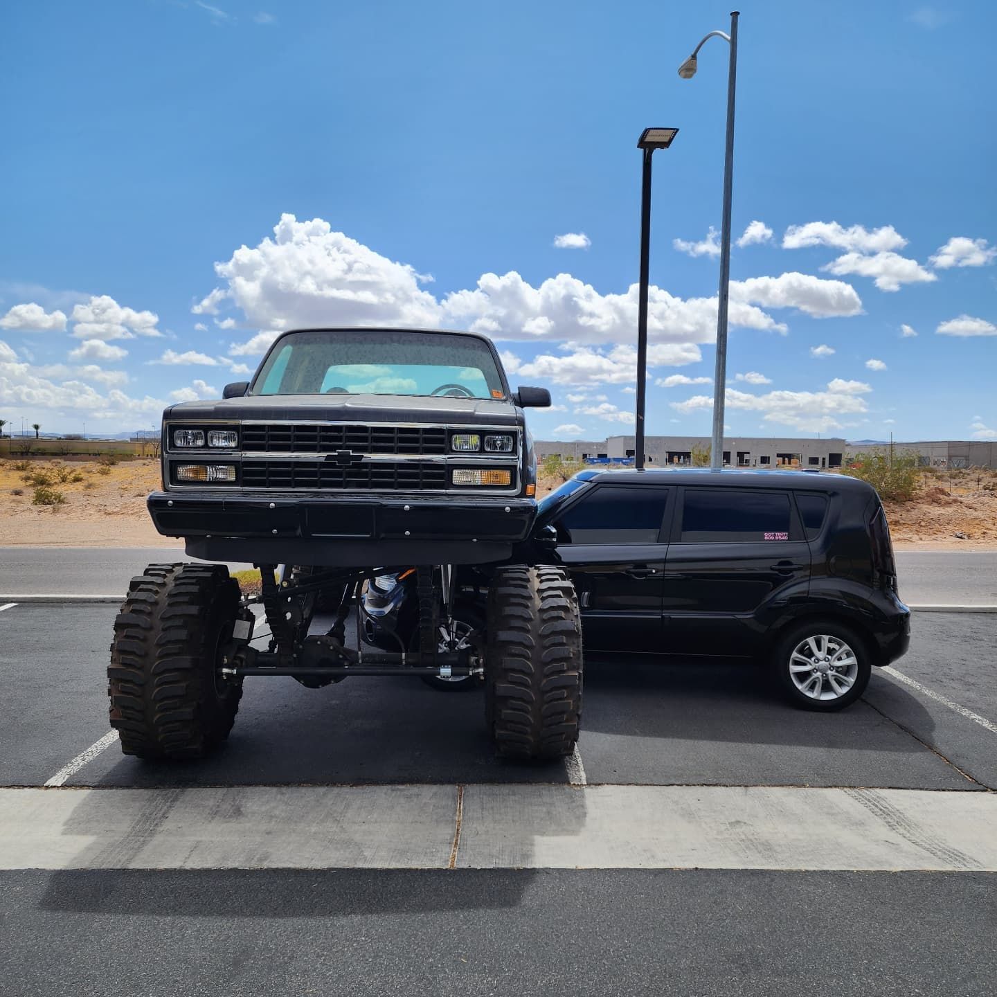 A black suv is parked next to a black truck in a parking lot