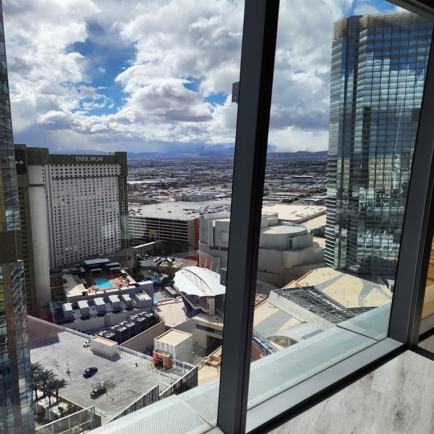 A view of a city from a window with a hotel in the background