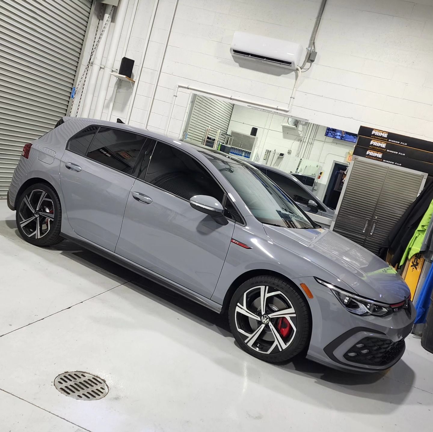 A gray car is parked in a garage next to a drain.