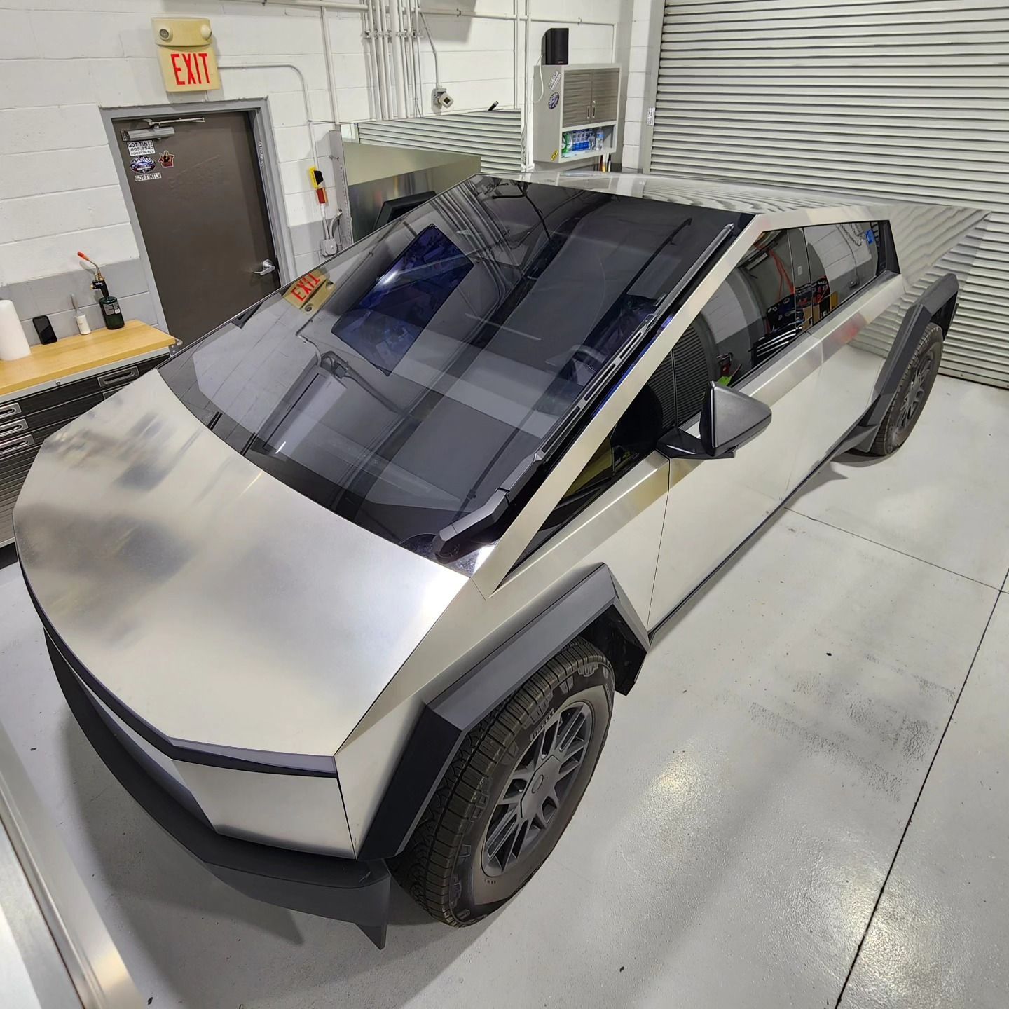 A silver car is parked in a garage with an exit sign above it