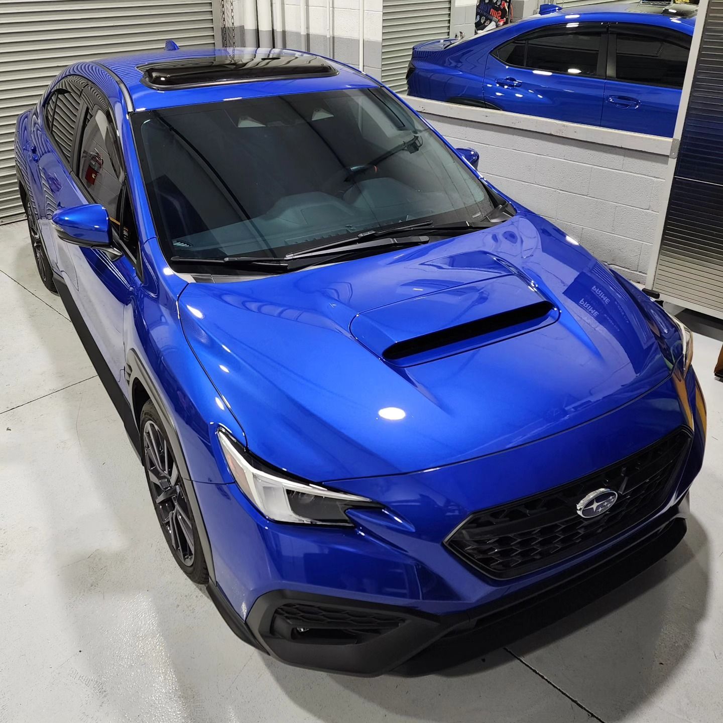A blue subaru wrx is parked in a garage
