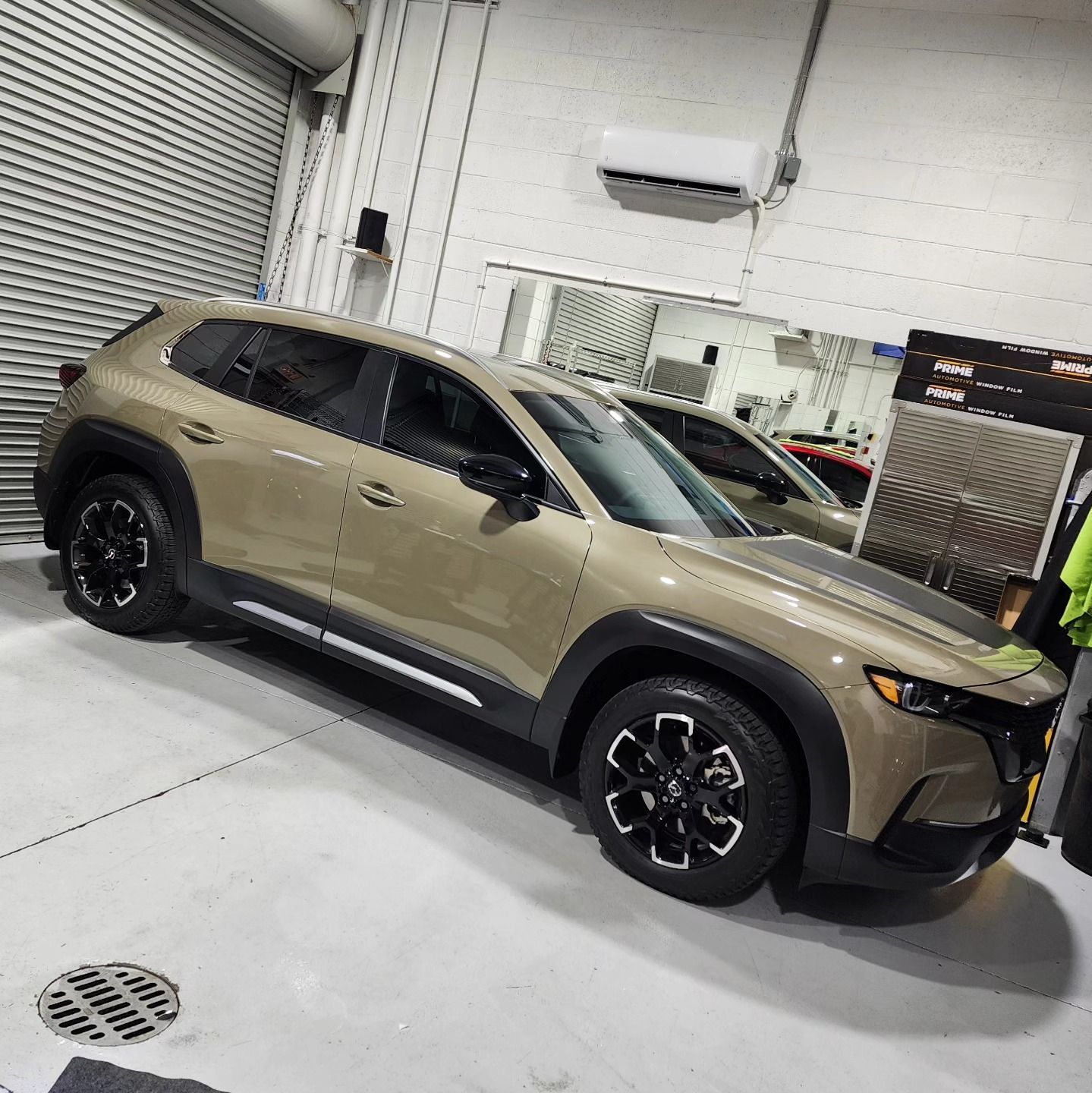 A car is parked in a garage next to a drain.