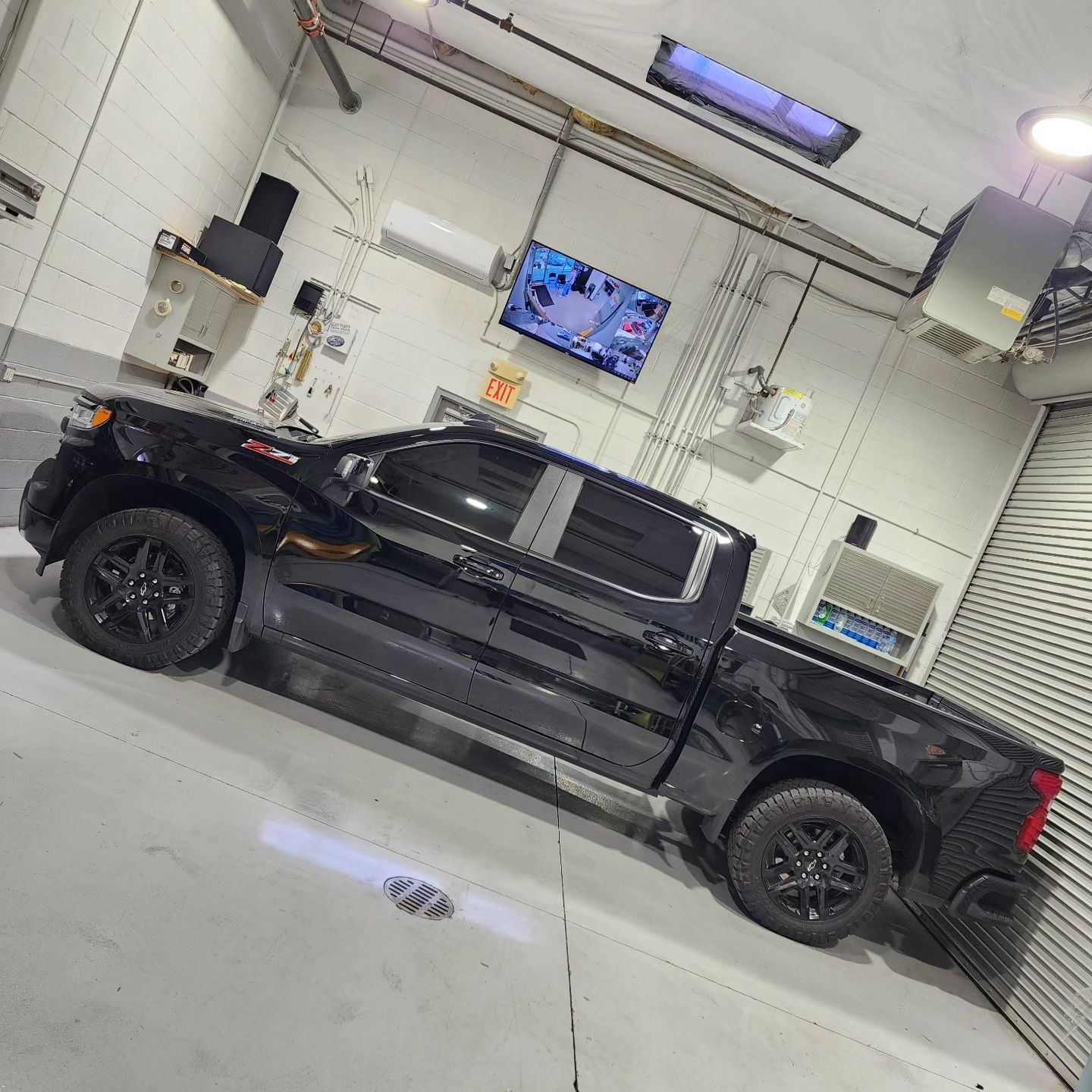A black truck is parked in a garage next to a television.