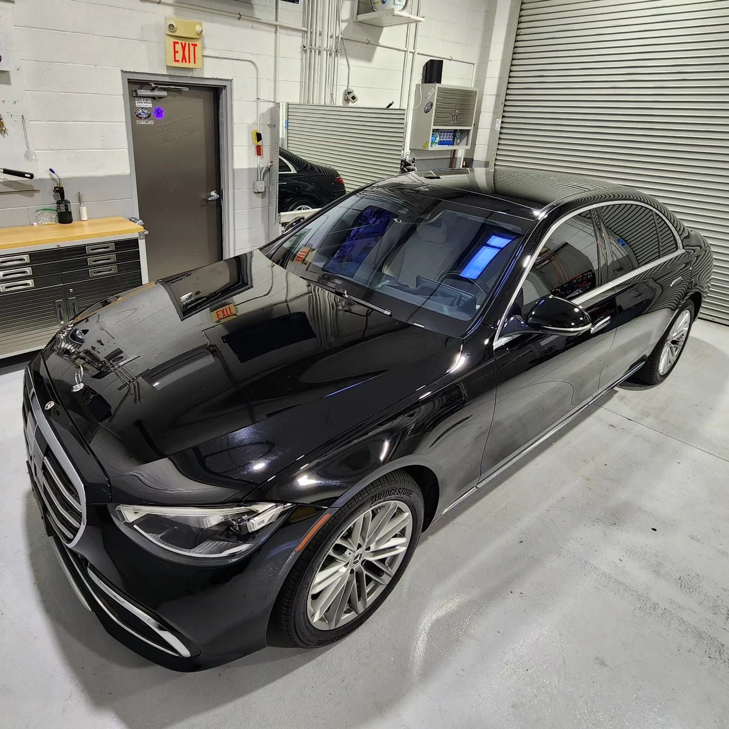 A black car is parked in a garage next to a garage door.