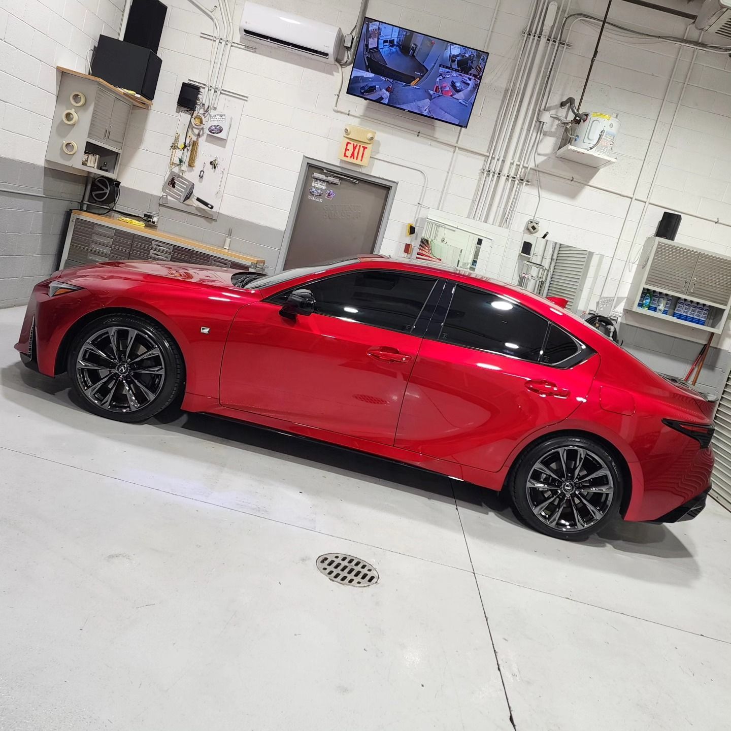 A red car is parked in a garage with an exit sign above it