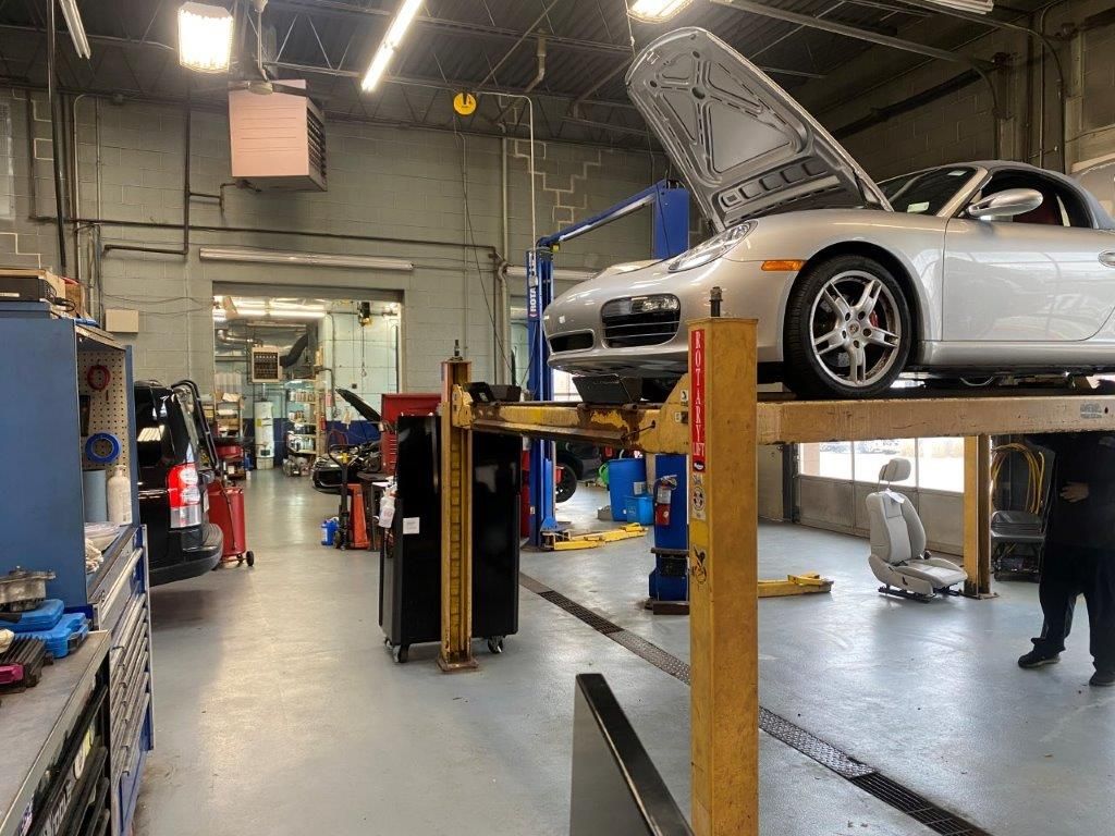 Silver car on a lift in an auto repair shop with tools and equipment nearby