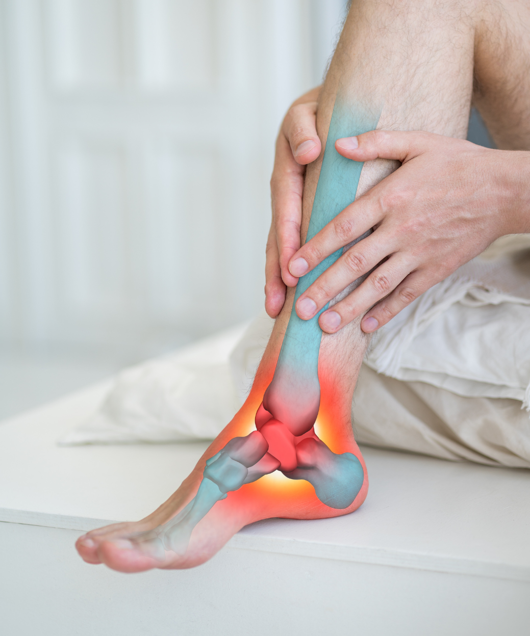 A man is sitting on a bed holding his ankle in pain.