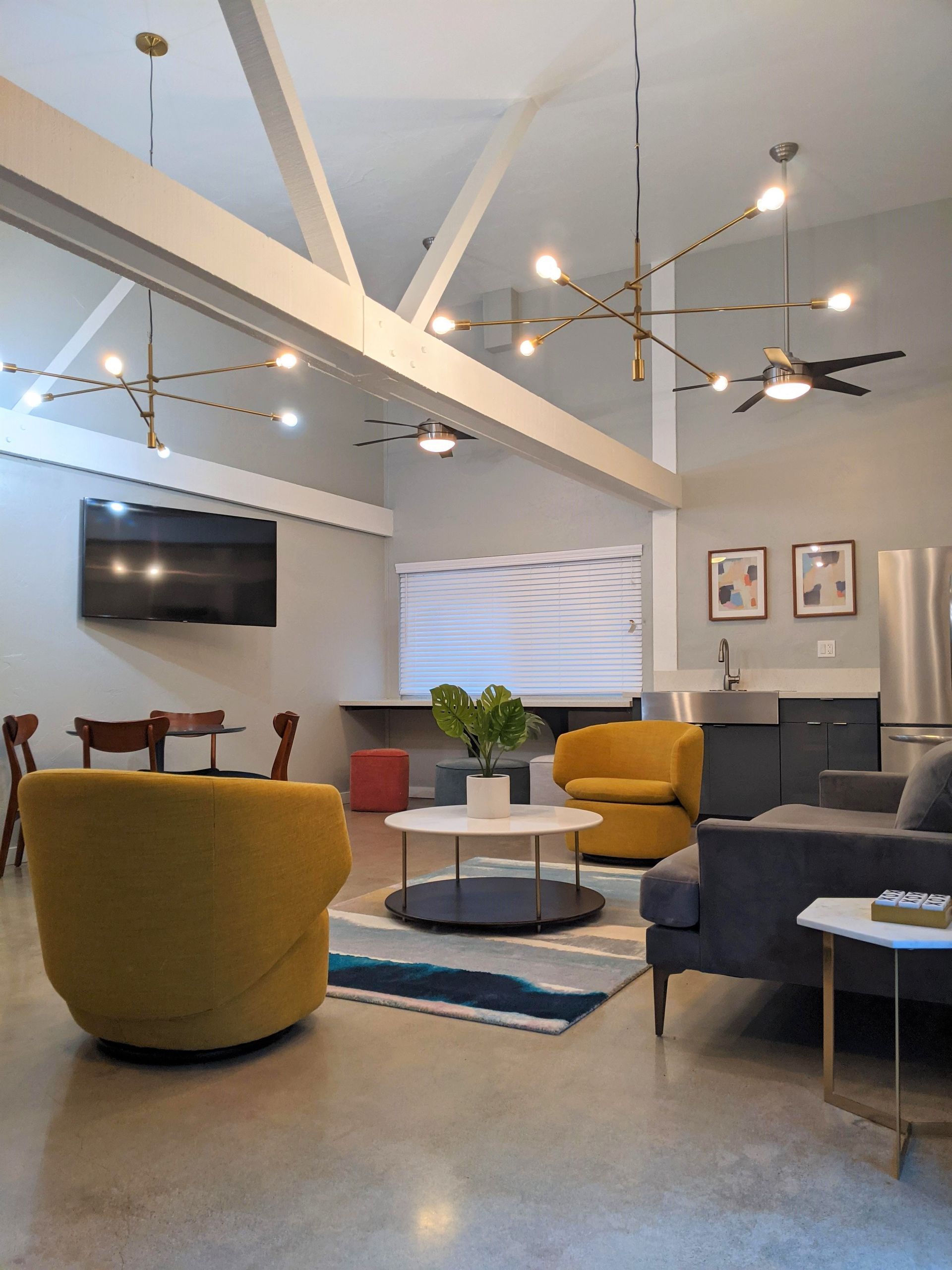 Clubhouse with yellow plush chairs, television, and ceiling fans and lights