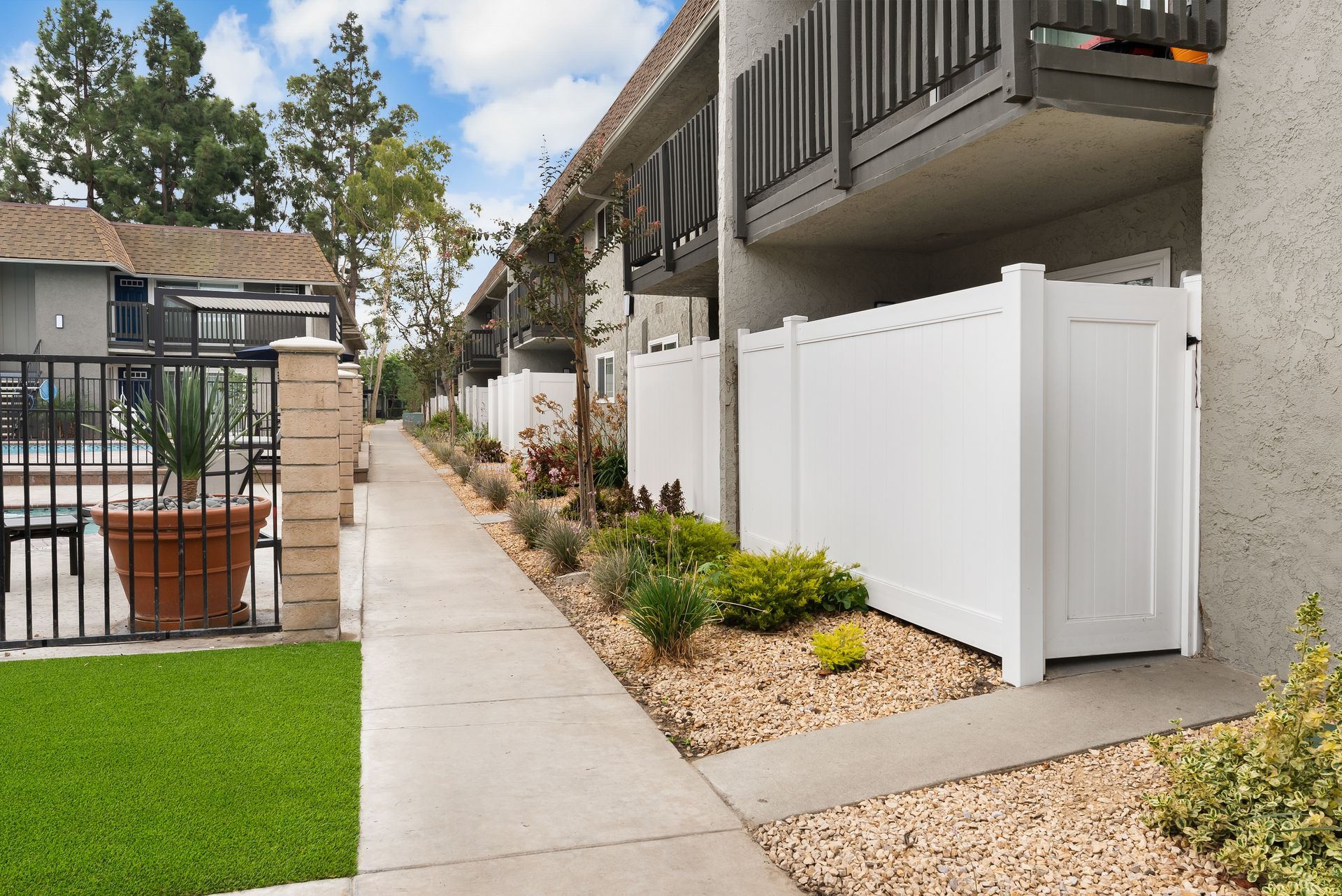 Landscape lined walkway with white fenced patio