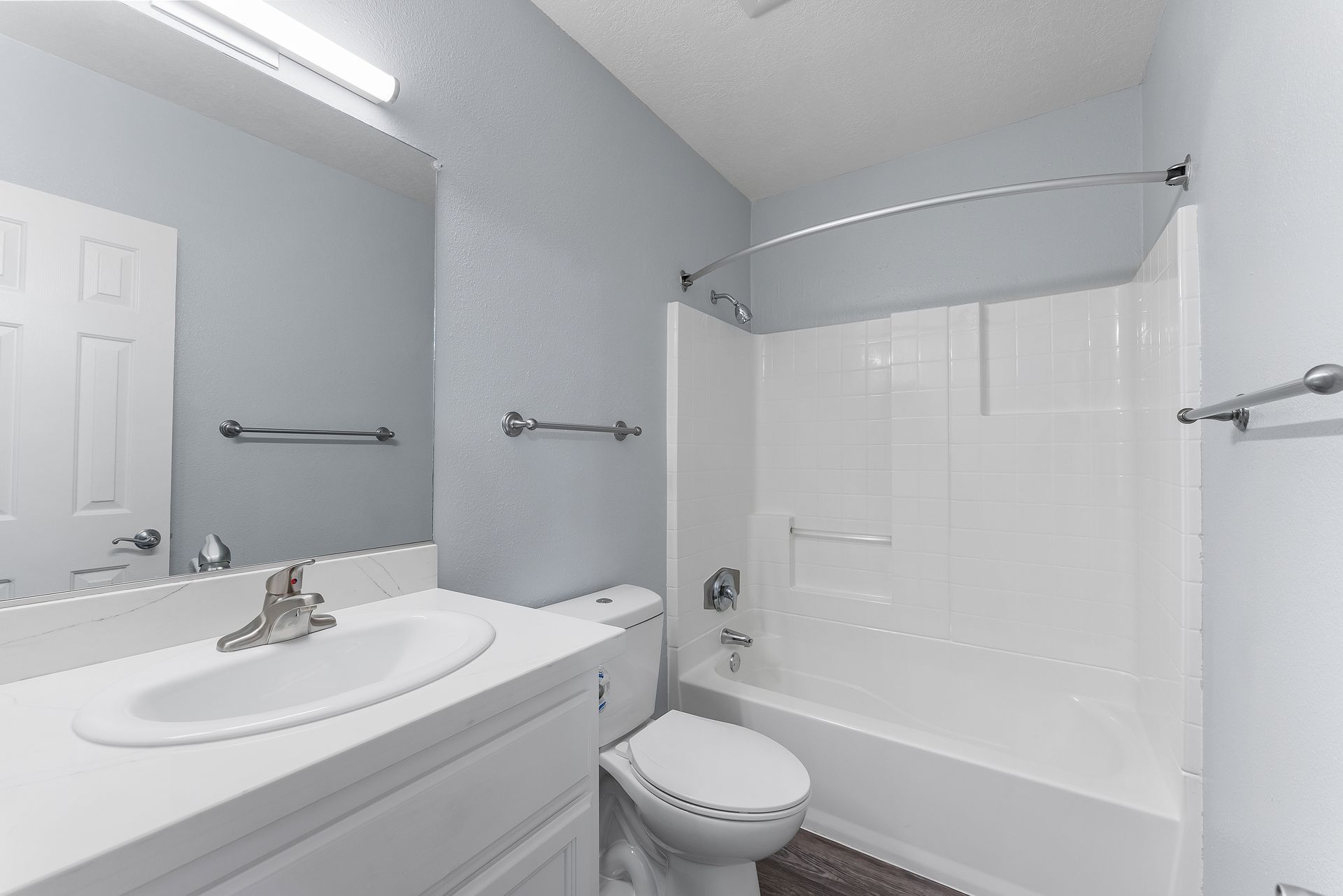 Bathroom with sink, toilet, shower tub, and white cabinets