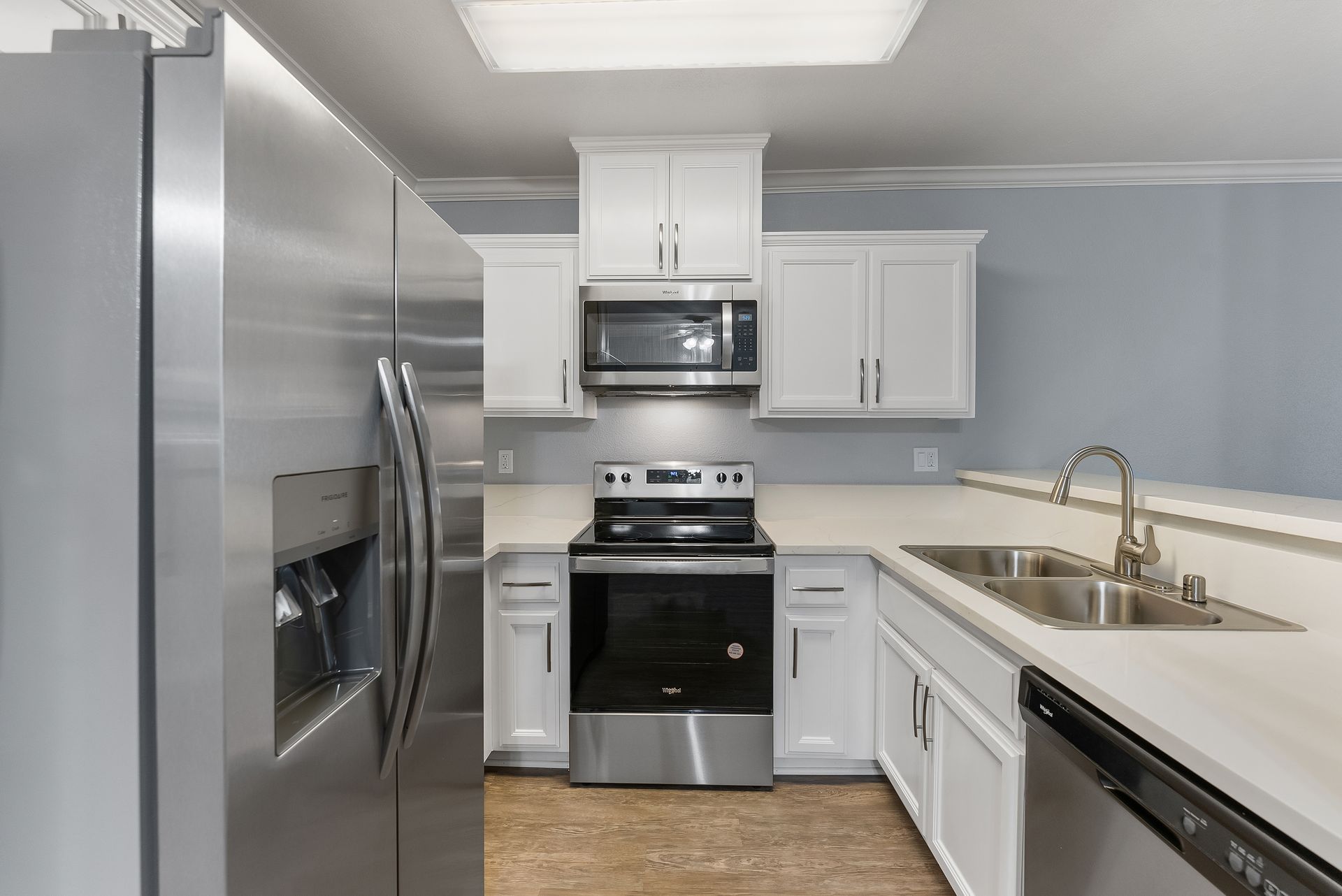 Interior kitchen with fridge, oven, and white cabinets