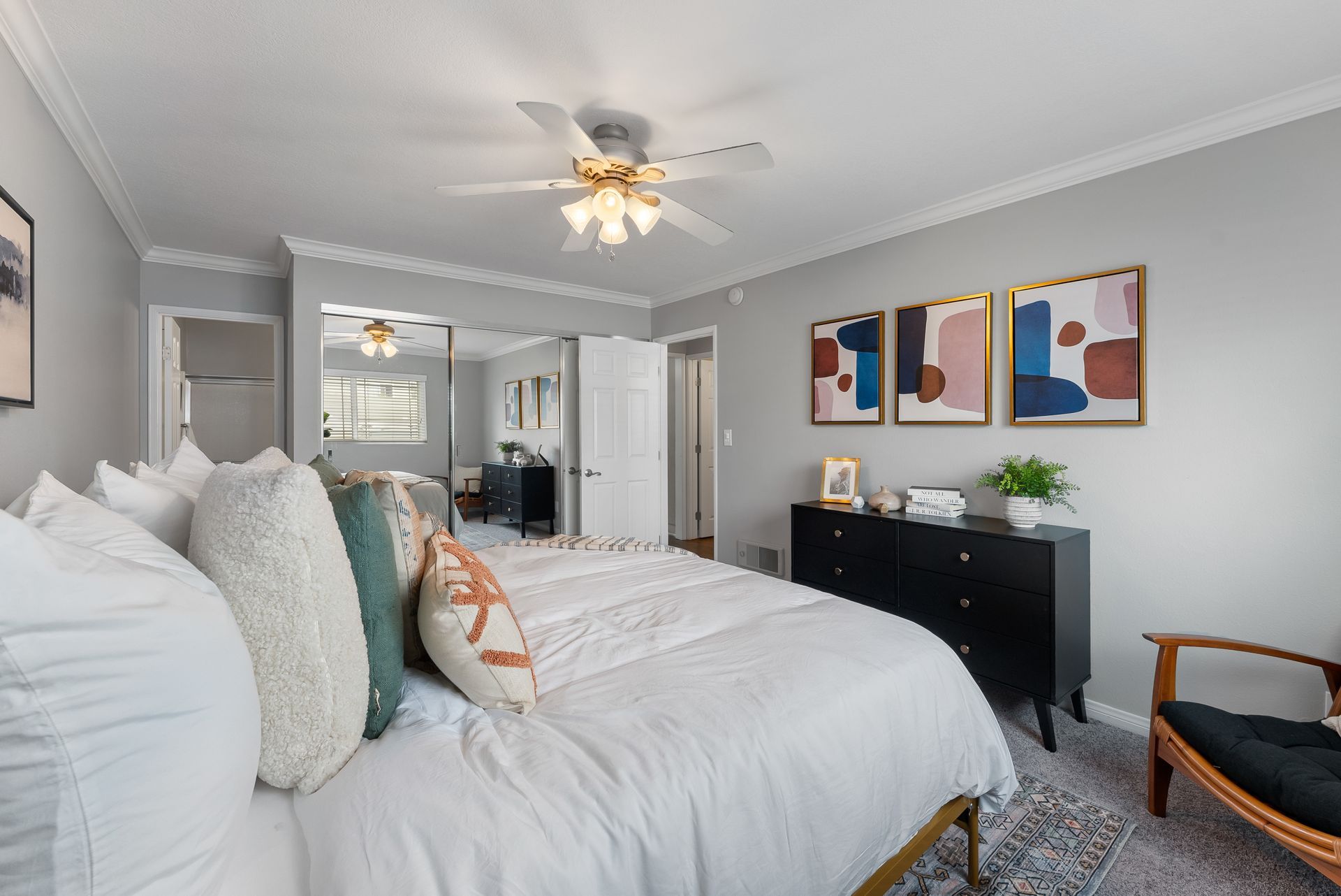 Master bedroom with queen sized bed with white bedspread from behind with door