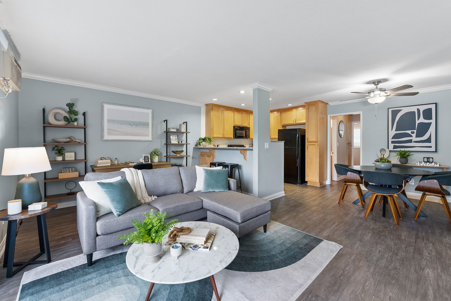 Interior living room with wood floors, white coffee table, and grey couch with pillows