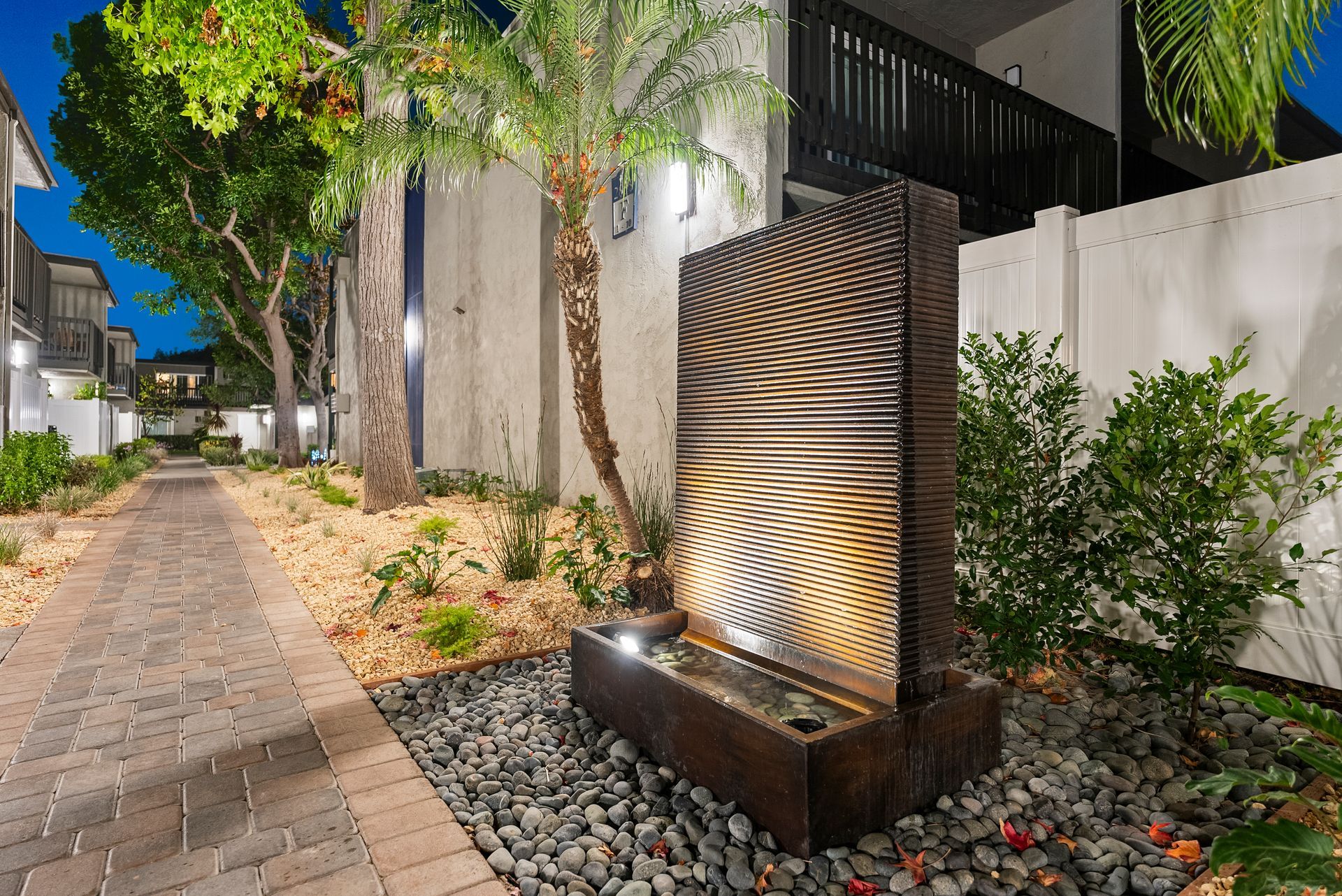 Standing fountain wall at dusk with lit palm trees from a diagonal