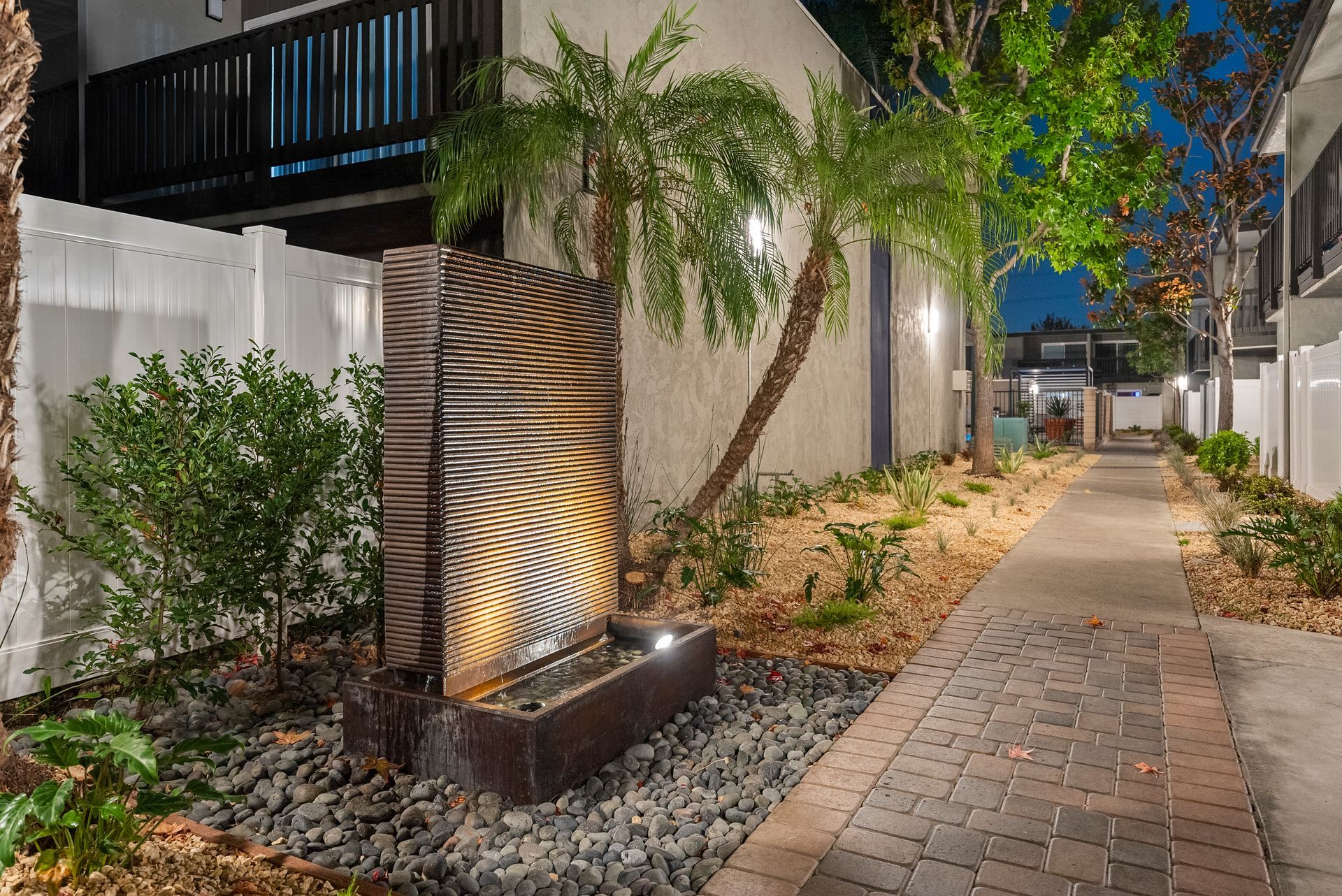 Standing fountain wall at dusk with lit palm trees from a diagonal