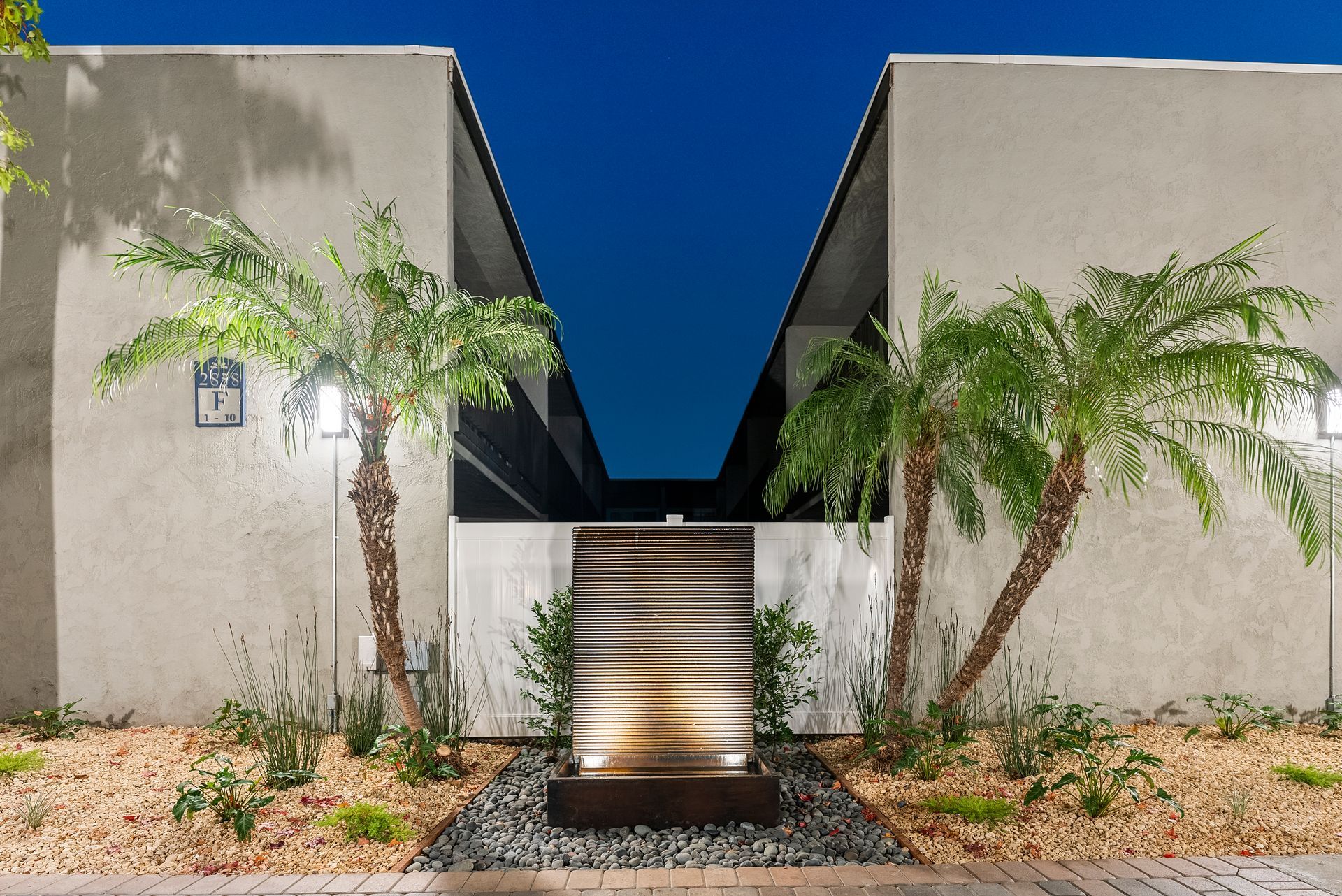 Standing fountain wall at dusk with lit palm trees fromstraight on