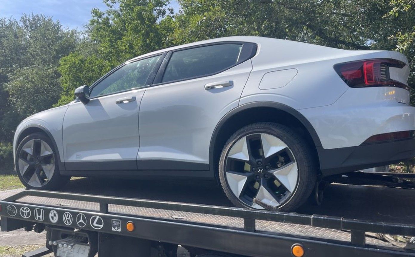 A white sedan on the back of a black tow truck in Westchester FL.