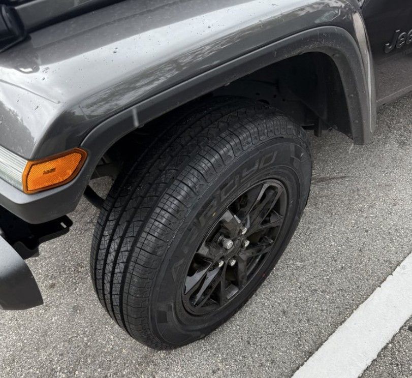 A gray jeep with a spare tire on.